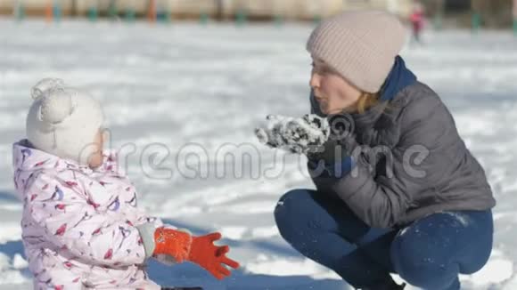 妈妈和女儿在一个美丽的冬天下雪的日子里在街上玩得很开心我妈妈向女孩扔雪女孩视频的预览图