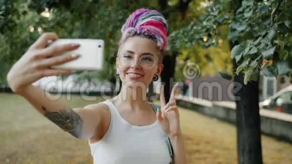时髦的年轻女士在城市公园自拍摆姿势微笑视频的预览图