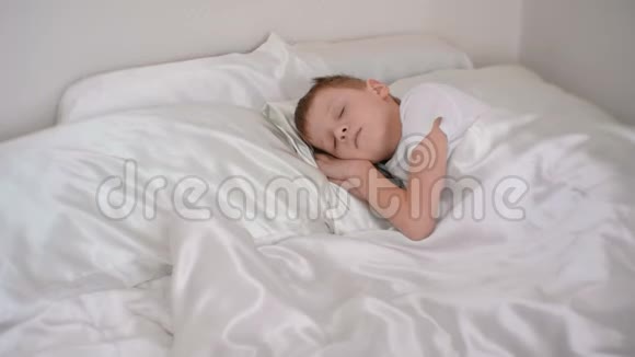 七岁的男孩静静地睡在他的房间里的床上把手放在他的头下视频的预览图
