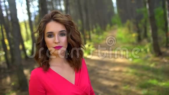 美丽少女穿着红色连衣裙在森林中健康长发的肖像快乐的女人在秋天的欢笑视频的预览图