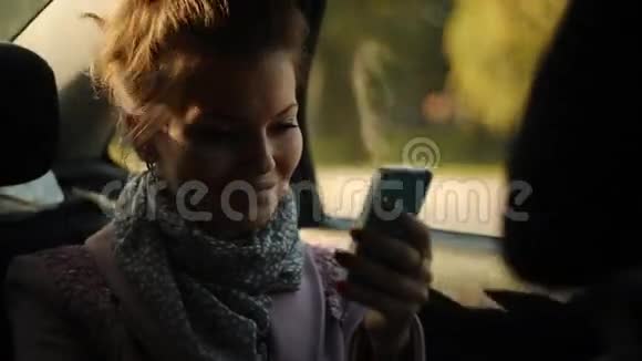 坐在车里的女孩看着你手机上的照片视频的预览图