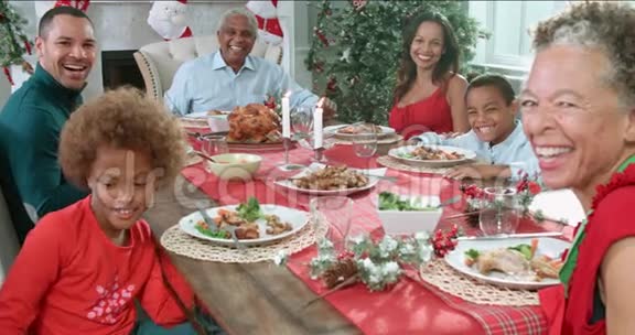 带着祖父母坐在餐桌旁享受圣诞大餐的家庭慢动作顺序看着镜头视频的预览图