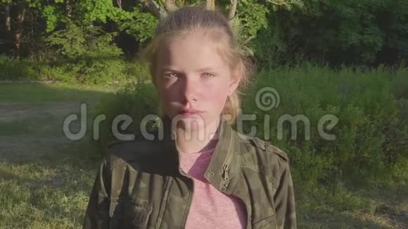 一张漂亮的十几岁悲伤女孩看镜头的特写肖像一头自然的金发一个幸福的微笑的白人孩子视频的预览图