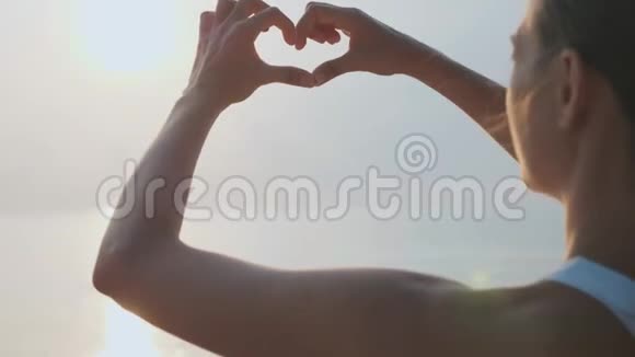 女性双手握着太阳耀斑的心形手势视频的预览图