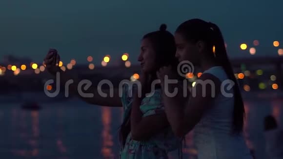 两个女朋友在一个夜城的背景上自拍慢动作视频的预览图