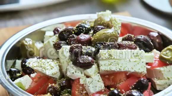 在希腊蔬菜沙拉中手动添加调味料的特写素食健康食品视频的预览图