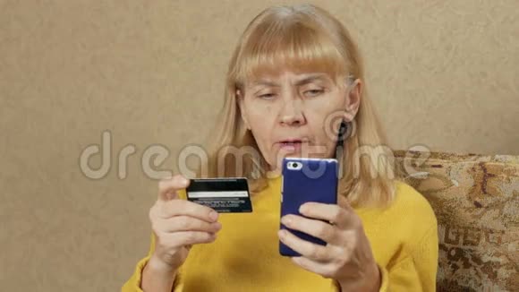 老年妇女在网上银行信用卡支付购买费用她仔细地把信用卡号码介绍给视频的预览图