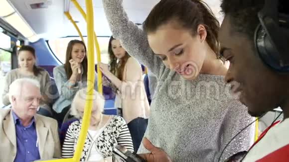 年轻夫妇在拥挤的公共汽车上看手机视频的预览图