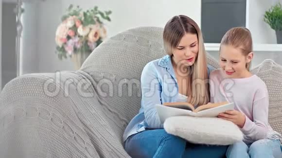 幸福的家庭母女两人笑着一起读纸质书一起享受周末视频的预览图