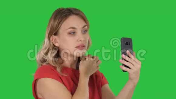 漂亮的女人用她的手机就像绿色屏幕上的镜子Chroma键视频的预览图