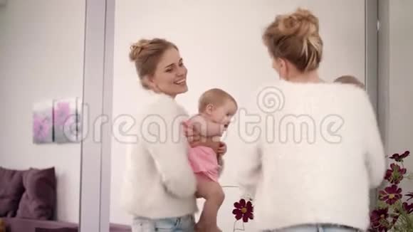 微笑的女人手上拿着婴儿跳舞美丽的家庭享受视频的预览图