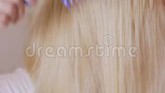 一位留着长发的金发女子正在镜子前梳头为染发根作准备视频的预览图