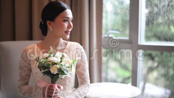 亚洲新娘穿着蕾丝连衣裙捧着美丽的白色婚纱闻着美丽的白色婚纱视频的预览图