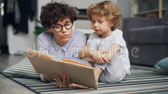 可爱的小男孩正在听童话故事而妈妈正在家里读故事视频的预览图