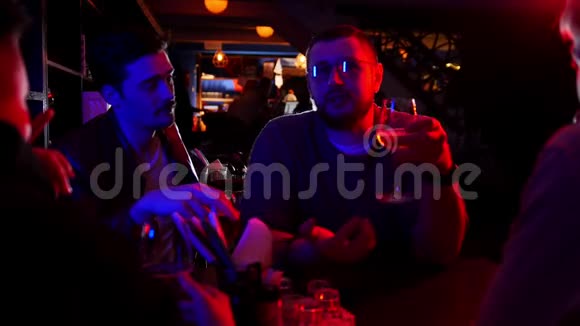 带霓虹灯的酒吧朋友们一起聊天戴眼镜的男人讲故事视频的预览图