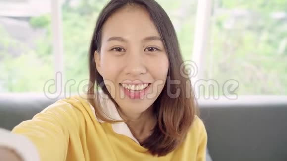亚洲博客女性使用智能手机录制vlog视频在家客厅女性享受有趣的时刻视频的预览图