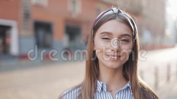 一个美丽的年轻女人看着镜头微笑着站在老街背景上的肖像女孩视频的预览图