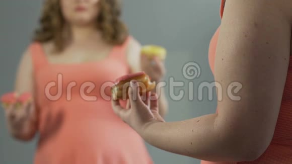 伤心的胖女孩对着镜子哭同时吃了两个甜甜圈视频的预览图