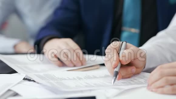 团队会议期间两位商人手持钢笔在纸质文件上展示细节视频的预览图
