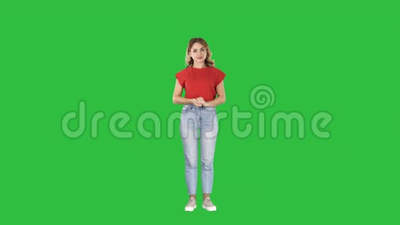 微笑的女人穿着休闲服装展示一些东西按下想象中的按钮在绿色屏幕上Chroma键视频的预览图