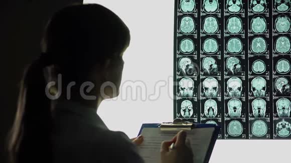 女神经科医生仔细地看着脑部x光写下诊断视频的预览图