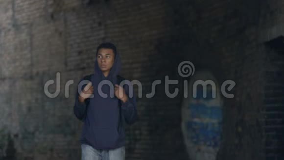 穿着连帽衫背着背包行走在危险的城市郊区的体贴的黑人少年视频的预览图