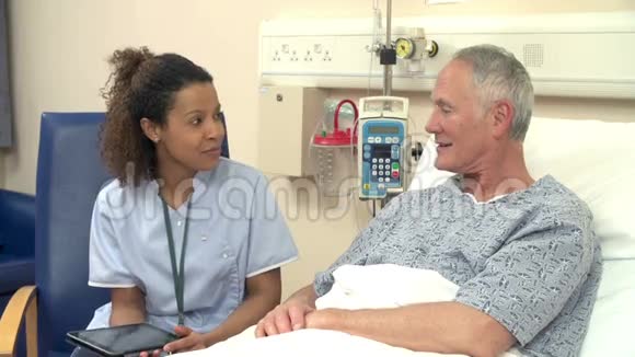 护士用数码平板电脑坐在男性病床旁视频的预览图