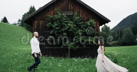 在田野的中间一对神奇的夫妇在一座小木屋前相遇视频的预览图