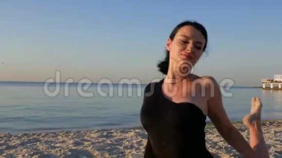 年轻健康的健身女性穿着黑色紧身衣在日出时在海边做瑜伽概念享受和谐4k4k视频视频的预览图