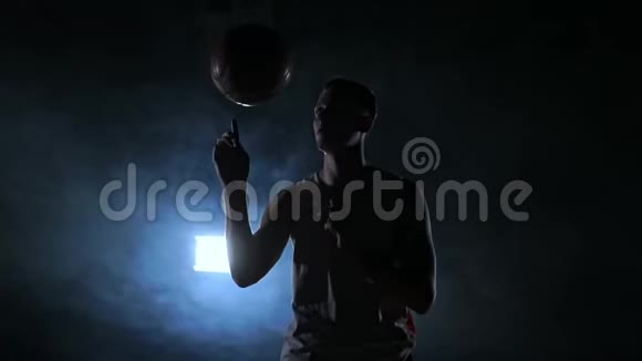 近镜头篮球运动员旋转球在他的手指黑暗的雾室与泛光灯视频的预览图