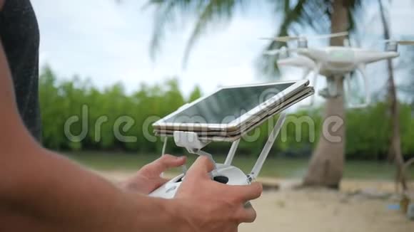 人控制飞行四重机通过遥控平板电脑小屏幕飞行员在海滩上练习飞行视频的预览图