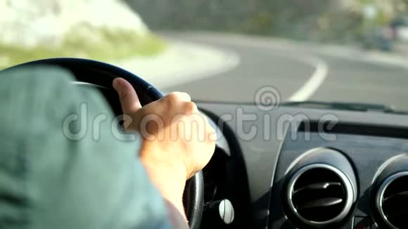 人类方向盘上的一只手缓慢地在沿着山脉的漫长道路上驾驶着一辆汽车3840x2160视频的预览图