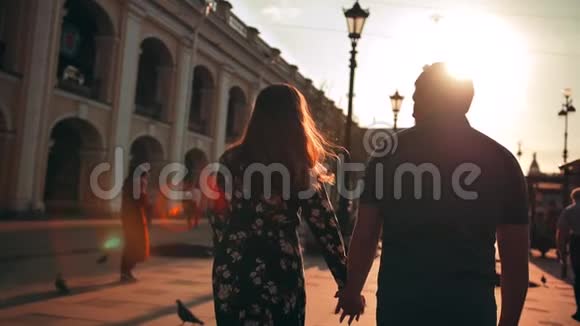 户外生活方式肖像年轻情侣在夕阳后的街道上漫步在城市中视频的预览图