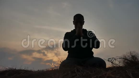 宗教观念一位在日落阳光下从事冥想生活的男僧的剪影佛教祷告视频的预览图