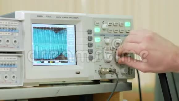 男子工程臂调整示波器以正确显示电信号现代小型工业视频的预览图