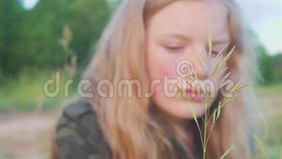 悲伤的金发女孩11岁的肖像又娇又梦幻地看着草叶视频的预览图