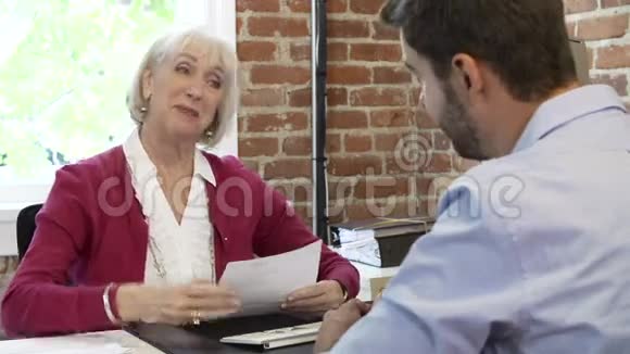 年长的女商人在办公室里采访年轻男人视频的预览图