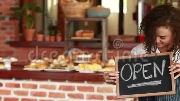 微笑的咖啡师手拿开放的招牌视频的预览图