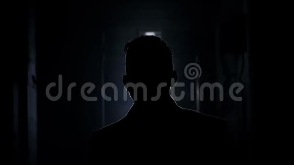 成熟男人的剪影沿着黑暗的走廊走向空亮的房间视频的预览图
