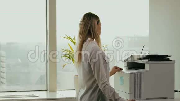 年轻女商人在办公室的打印机上打印视频的预览图