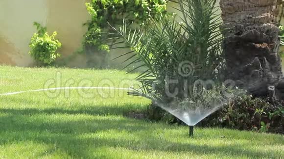 灌溉设备洒水车在花园的绿草上喷洒水珠视频的预览图