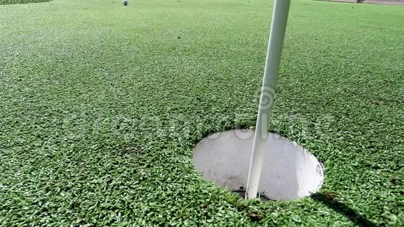 白色高尔夫球击打旗棒在放绿色球时掉进洞里视频的预览图