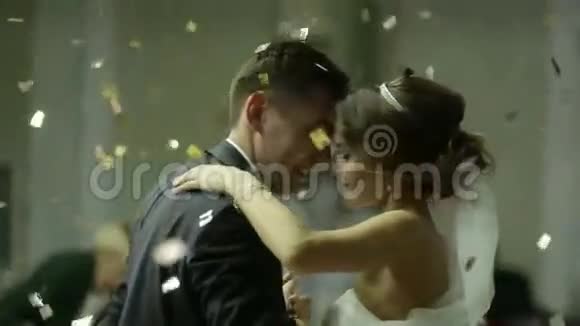 美丽的黑发新娘和英俊的新郎在婚礼上跳舞空中的纸屑非常招标视频的预览图