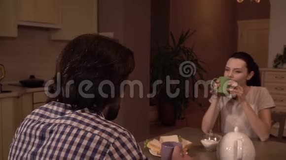 男人和女人坐在桌子旁吃晚饭她从格林杯里喝酒看着丈夫他吃烤面包看起来视频的预览图