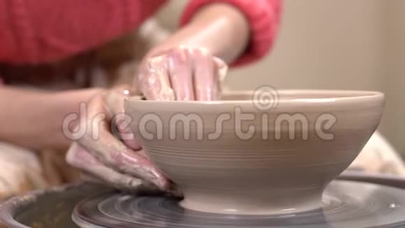 特写侧面的一个泥泞的手微调粘土器的形状在旋转陶器的车轮视频的预览图