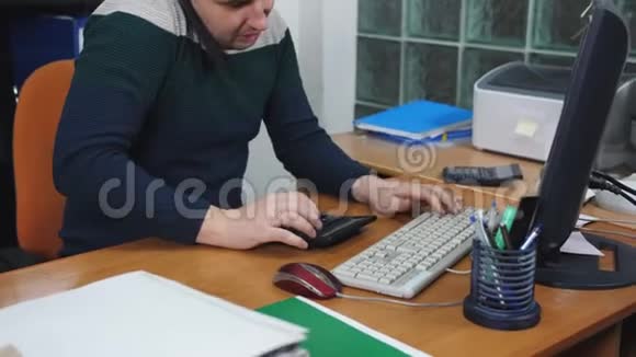 在办公室工作的人在电脑上工作在电话上交谈并考虑使用计算器视频的预览图