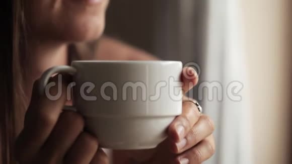 年轻漂亮的女人坐在窗边喝茶视频的预览图