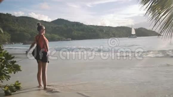 一位年轻女子站在海滩上呼吸新鲜空气的侧面肖像视频的预览图