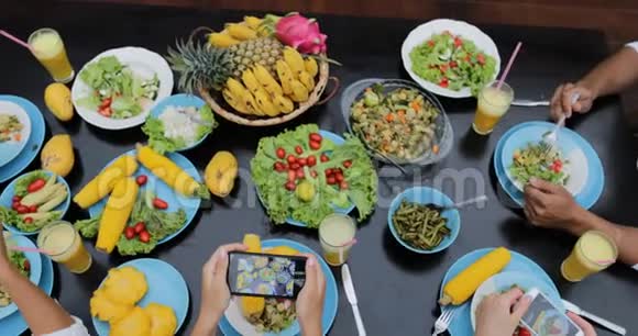 以手机智能手机顶部视角拍摄健康素食照片的人组坐着吃饭的朋友视频的预览图