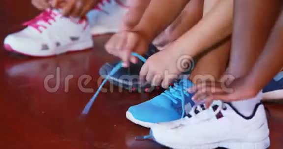 在篮球场系鞋带的女孩视频的预览图